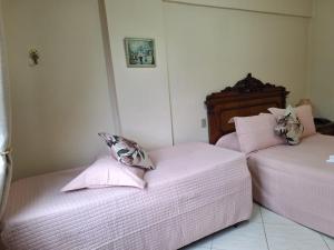 two beds in a room with pink sheets and pillows at Flats Cavalinho Branco 405 ou 603 in Águas de Lindoia