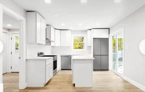 a white kitchen with white cabinets and white appliances at Hamptons Tiana Bay Oasis in Hampton Bays