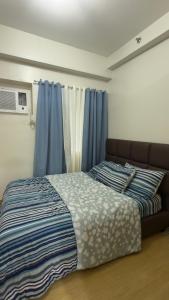a bed in a room with blue curtains at TIRPT Staycation in Manila +50 photos