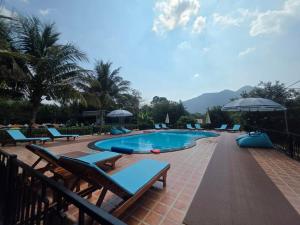 a swimming pool with lounge chairs next to a resort at Khao Sok Country Resort in Khao Sok National Park