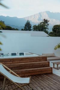 a deck with a hot tub and a chair on a roof at Lodge des palmiers - jacuzzi in Salazie