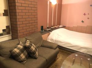 a living room with a couch and a bed at ホテルアドレ大人専用 in Hachinohe