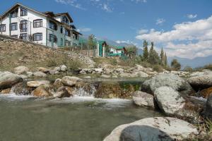 a river with rocks in front of a building at Hotel grandlords in Pahalgām