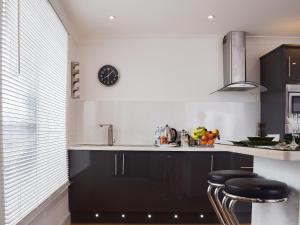 a kitchen with a counter with stools and a clock on the wall at Bramble Cottage in Leven