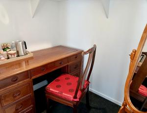 a desk with a red chair next to a wooden desk at Executive King Suite - Ensuite in Holmview