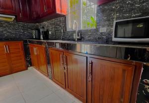 a kitchen with wooden cabinets and a microwave at Villa Rosa in San Felipe de Puerto Plata