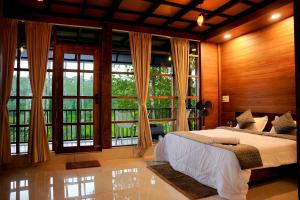 a bedroom with a large bed and large windows at Ethnic Villa Wayanad in Kenichira