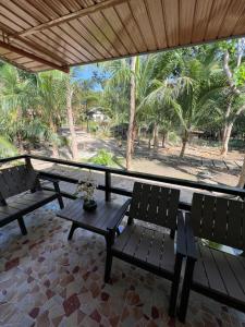 a porch with benches and a table and palm trees at Dutch Guest House Studio in Siquijor