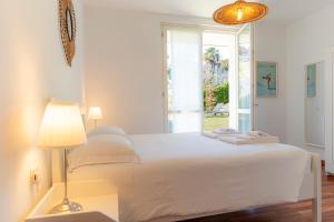 a white bedroom with a bed and a window at giardino e piscina apartment in Bellagio +86 photos