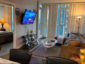 a living room with a couch and a tv at Spacious-Cozy 2Bed Condo in Square Ones Misissauga in Mississauga