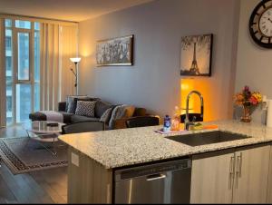 a kitchen with a sink and a living room at Spacious-Cozy 2Bed Condo in Square Ones Misissauga in Mississauga