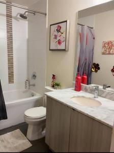 a bathroom with a sink and a toilet and a tub at Spacious-Cozy 2Bed Condo in Square Ones Misissauga in Mississauga