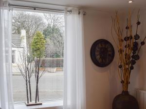 a window with a white curtain and a clock on the wall at Bramble Cottage in Leven