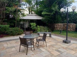 a patio with a table and chairs and an umbrella at Cobertura duplex Landmark jardins in São Paulo
