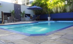 a large blue swimming pool with chairs and an umbrella at Cobertura duplex Landmark jardins in São Paulo