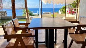 a wooden table and chairs with a view of the ocean at Siquijor Jade ocean resort in Siquijor