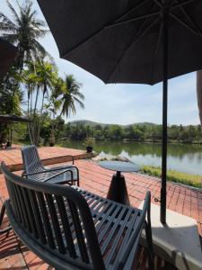 a patio with two chairs and a table with an umbrella at Base 22 Hatyai in Ban Rai