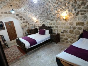 ein Schlafzimmer mit zwei Betten und einer Steinwand in der Unterkunft Rumetpaşakonağı in Mardin