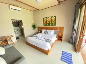 a bedroom with a large bed and a couch at Nada Garden villa in Jinengdalem +4 photos