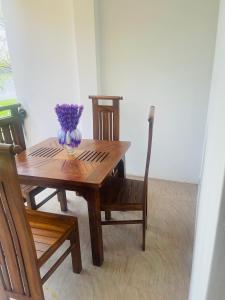 a wooden table with a vase of purple flowers on it at Sedna hotel in Mahawewa