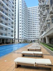 a row of chaise lounges in a building with a pool at Blanc Suite in Pasong Bayog