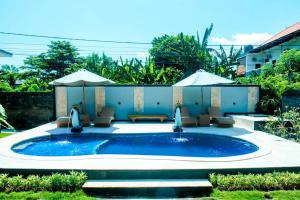 a pool with chairs and umbrellas in a yard at Nada Garden villa in Jinengdalem