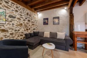 a living room with a couch and a stone wall at Gîte Léon - Au cœur du village 4 pers in Gargilesse-Dampierre
