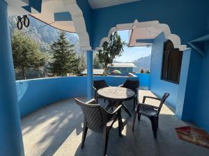 a patio with a table and chairs on a blue wall at Gauri Homestay in Pithorāgarh