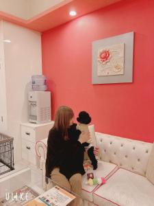 a woman sitting on a couch holding a dog at NUDA Toyama in Takaoka