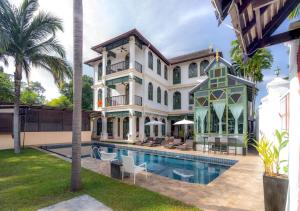 a large mansion with a swimming pool and palm trees at Cheva Gallery Boutique Hotel in Chiang Mai