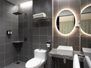a bathroom with a toilet and a sink and a mirror at Green Hotel in Puchong