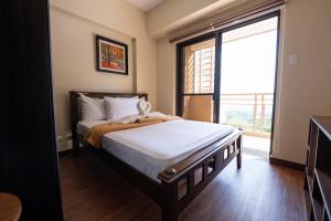 a bedroom with a bed and a large window at 2BR Cloud 512 with Parking Slot in Baguio
