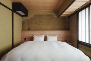 a bedroom with a large white bed with two pillows at MUDANI 達磨町 Darumacho in Kyoto