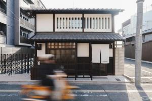 a person riding a scooter in front of a building at MUDANI 達磨町 Darumacho in Kyoto