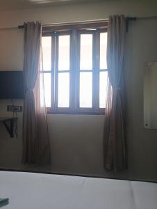 a window with curtains in a room at Joyous Rooms in Cherrapunji