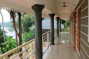 a balcony with columns and a view of the river at SHANKARAM Homestay in Kodanad