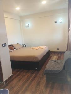 a bedroom with a bed and a chair in it at Joyous Rooms in Cherrapunji