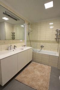 a bathroom with two sinks and a tub and a mirror at Bird's eye Apartment with sea view 18th floor in Klaipėda +12 photos