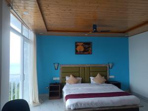 a bedroom with a blue wall with a bed and a window at Elite peak hotel in Kasauli +15 photos