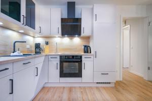 a kitchen with white cabinets and a sink and an oven at Lütt Mööv - Seestraße 8 4 in Kellenhusen