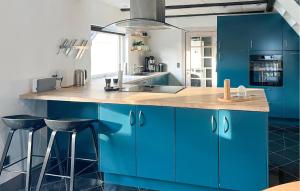 a blue kitchen with blue cabinets and bar stools at Stunning Home In Sæby in Sæby