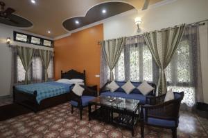 a bedroom with a bed and a couch and a table at Trisha Heritage in Dibrugarh