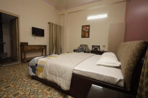 a bedroom with a bed and a television in a room at Trisha Heritage in Dibrugarh