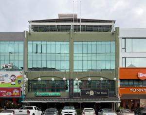 a building with cars parked in a parking lot at Green Hotel in Puchong