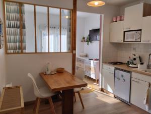 a small kitchen with a wooden table and chairs at Coté Lac mini in Mimizan