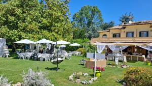 a garden with tables and umbrellas and a building at Osteria del Cavaliere B&B e Maneggio in Sacrofano