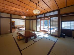 a living room with a table and a room with windows at Wanosato in Takayama