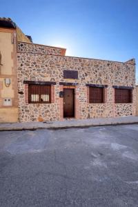 a stone building with a door and two windows at Los Abuelos Carreros in Consuegra