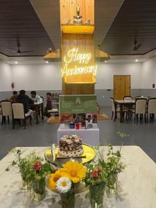 a table with a cake and flowers on a table at The Lazymojo in Tāla