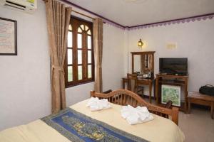 a bedroom with a bed and a window and a tv at Ban Ao Thong in Trang